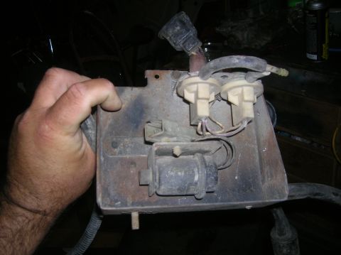 1985 Ford Bronco - This automotive electrical part features multiple connectors and wiring, held by a hand for inspection.