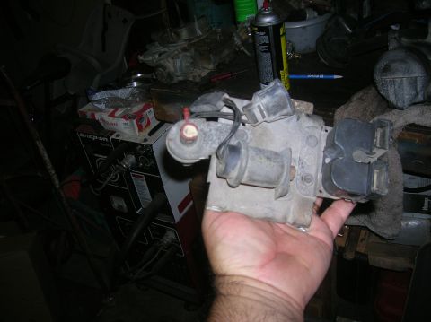 1985 Ford Bronco - An automotive part is held in a hand, with a Snap-on welder and other garage items visible in the background.