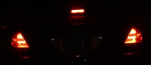 Night closeup of car rear with red LED taillights and lit center high-mount brake light
