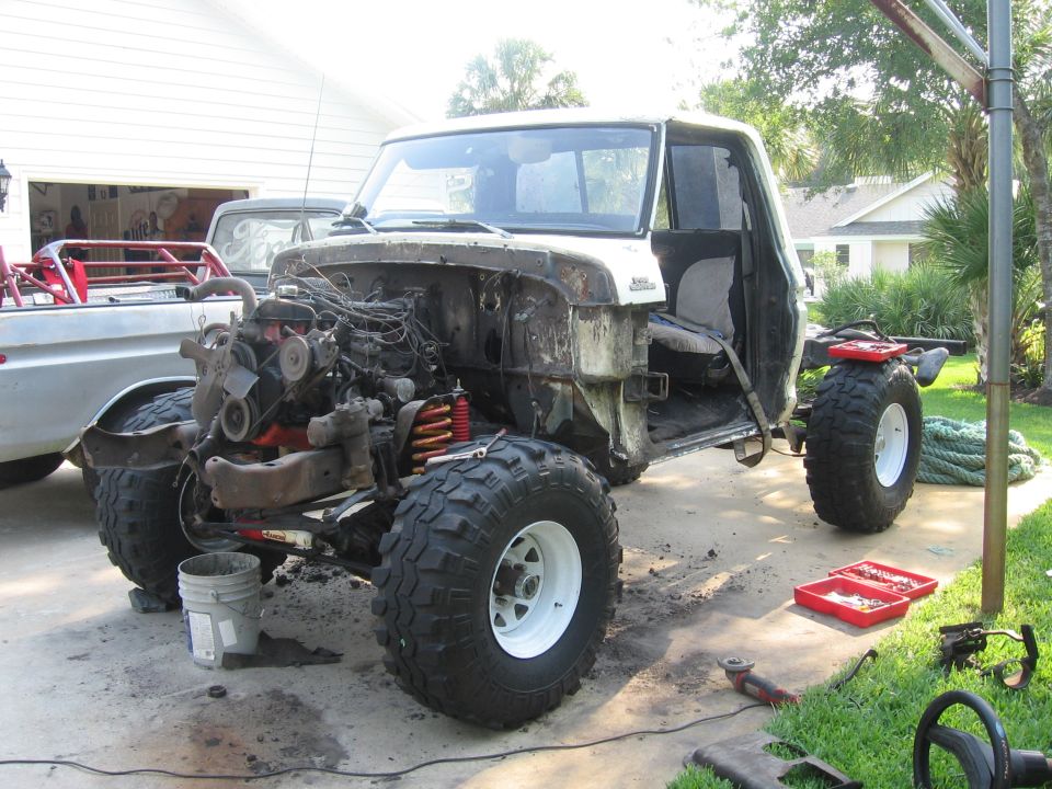 1979 Ford F-150 chassis with engine exposed, cab present, and another truck in background
