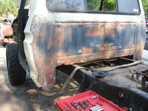 1979 Ford F-150 - This heavily rusted truck bed is undergoing repair, revealing its underlying frame and a set of tools.