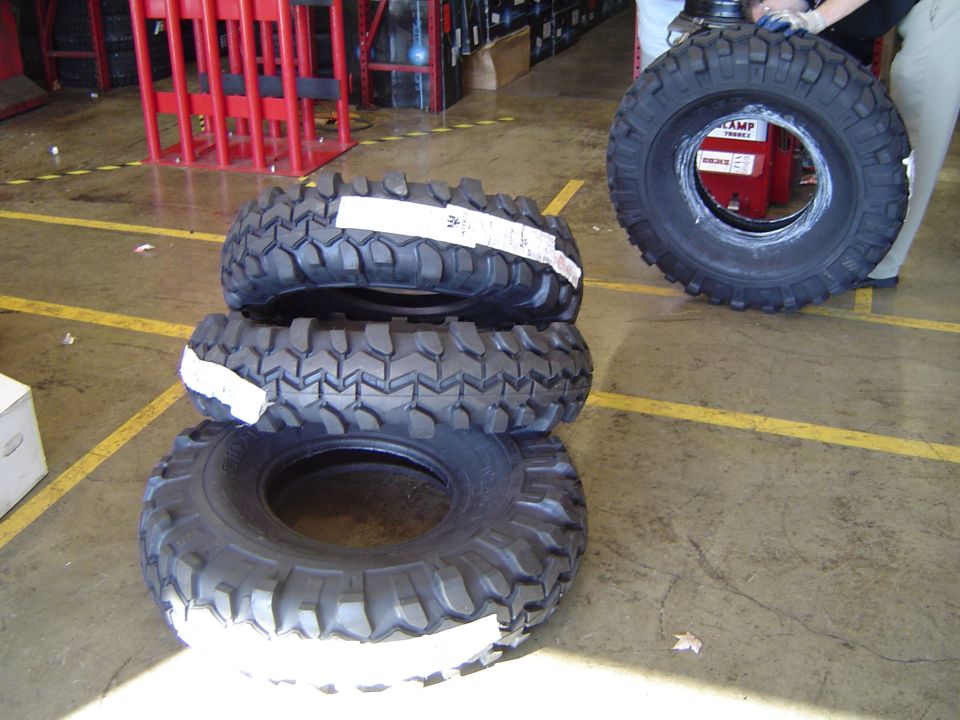 Four off-road mud-terrain tires staged on a warehouse floor