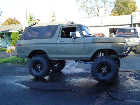 1978 Ford Bronco - This lifted 1978 Ford Bronco features a soft top and aggressive off-road tires, parked in a driveway.