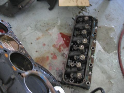 1979 Ford F-150 - Engine components, including a cylinder head and part of an engine block, are visible on a concrete surface, possibly during a repair or re…