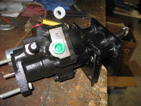 1979 Ford F-150 - Freshly painted black hydraulic brake booster and master cylinder assembly bolted to a fabricated mounting bracket, resting on a wooden wor…