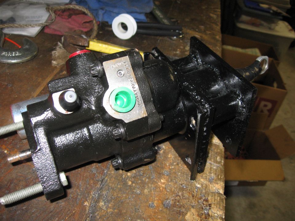 Black-painted hydroboost brake booster and master cylinder on bracket sitting on a workbench