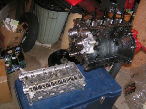 1996 Ford Probe - Disassembled engine components rest on a blue container amidst garage clutter.