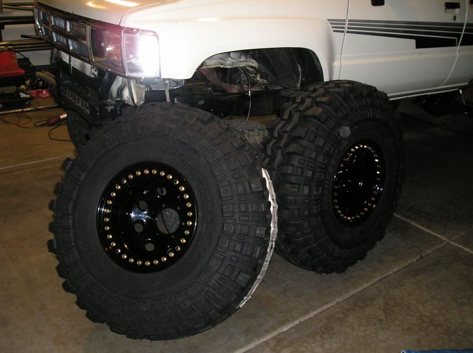 1986 Toyota Hilux front end with large off-road tires mounted on black beadlock wheels