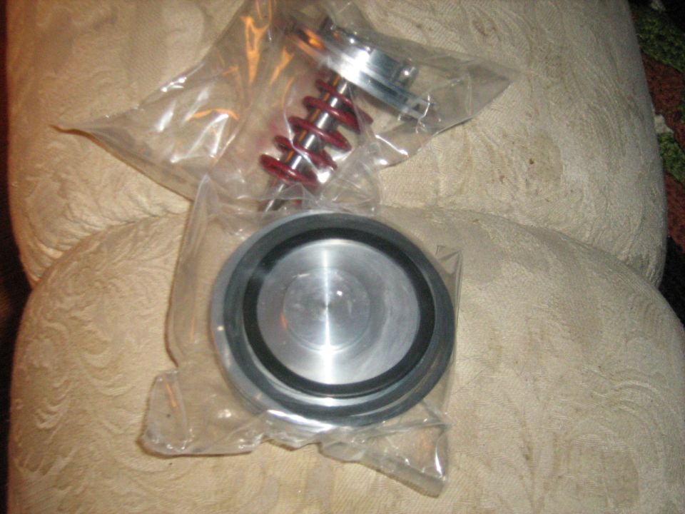 Coilover shock and a machined ring in plastic bags on a couch