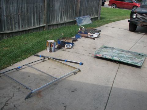 1966 Ford Bronco - 1966 Ford Bronco front end and various parts are staged on a concrete driveway.