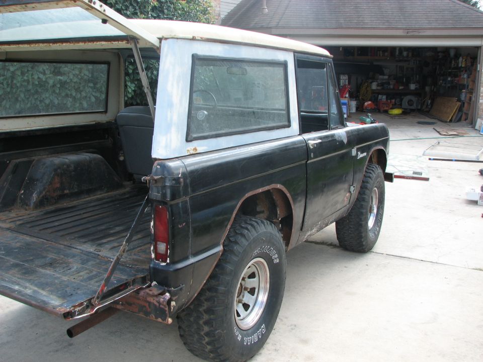 Black 1966 Ford Bronco with white hardtop, tailgate down, parked in driveway