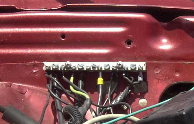 Red car's engine bay showing a terminal block with wires and a SuperMotors.net watermark