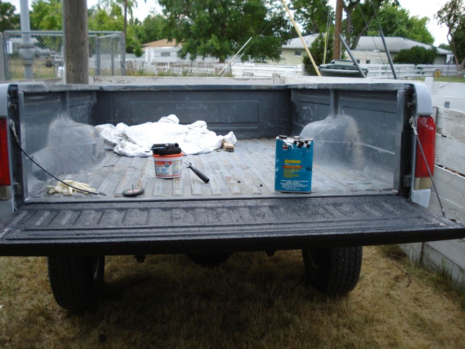 Truck bed with paint can, roller, gloves, and acetone can