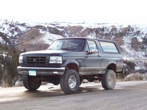 1994 Ford Bronco - This lifted 1994 Ford Bronco is captured in a three-quarter front view against a backdrop of snowy hills.