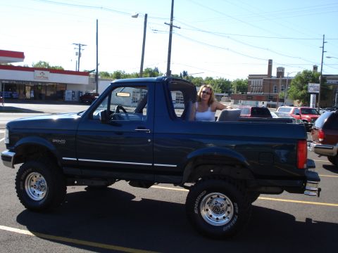 1994 Ford Bronco - Side view of a 1994 Ford Bronco with a woman sitting in the rear passenger area.