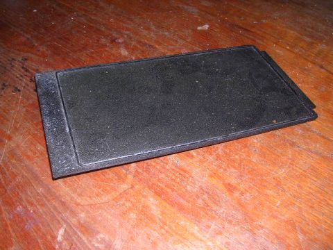 1975 Ford Ranchero - A black rectangular part rests on a wooden surface.