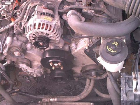 2000 Ford Crown Victoria - Front of a V8 engine with the serpentine belt removed, exposing the bare crank pulley, alternator pulley, idler and tensioner pulleys. The…