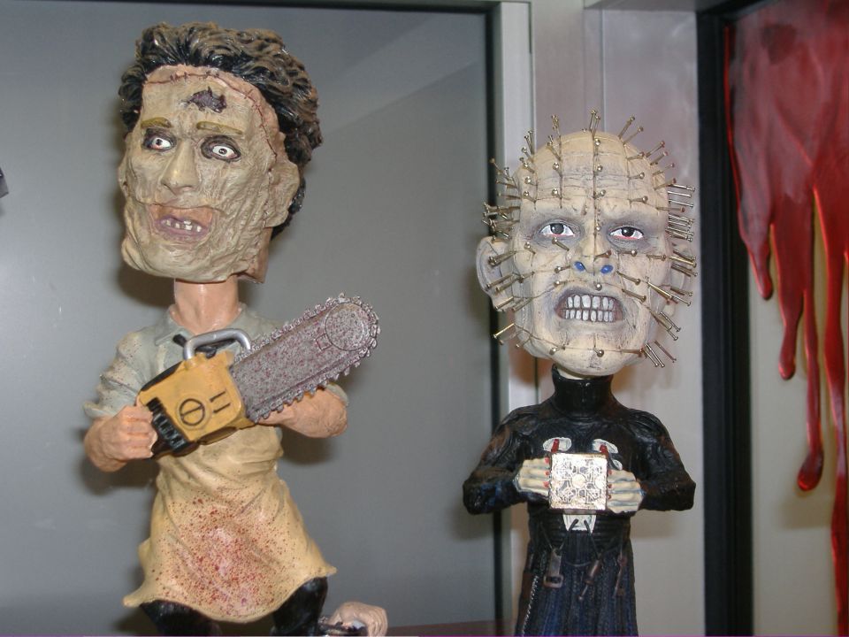 Two horror movie figures, one with a chainsaw and apron, the other with pins in its face
