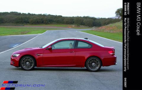 2002 BMW M3 - A red BMW coupe is captured in a side profile on a paved track with a wooded area in the background.