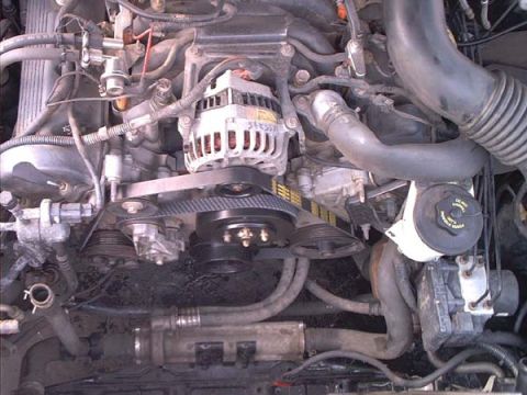 2000 Ford Crown Victoria - Overhead view down into the front of a V8 engine bay showing the serpentine belt routed around the crank pulley, alternator with a handwrit…
