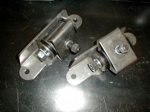 1996 Ford Bronco - Two metal engine mounts with rubber dampeners and bolts are shown on a dark, textured surface.