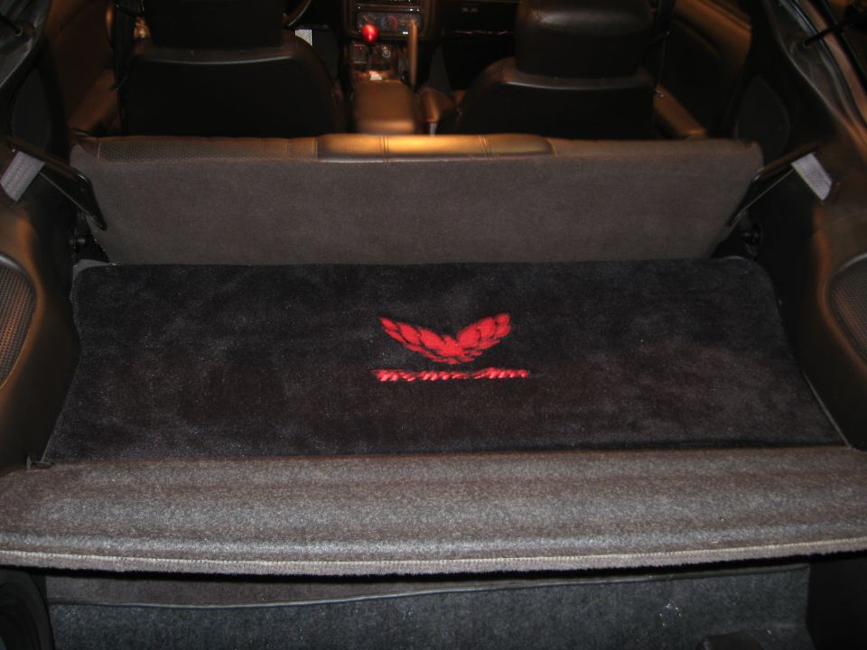 Car interior with red Trans Am emblem on carpeted area. 2002 Pontiac Trans Am