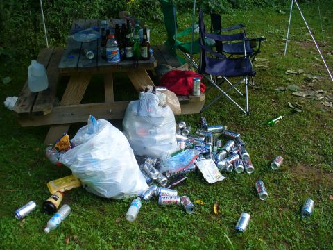 1991 Ford Probe - A picnic site littered with empty bottles, cans, and trash bags after an event.