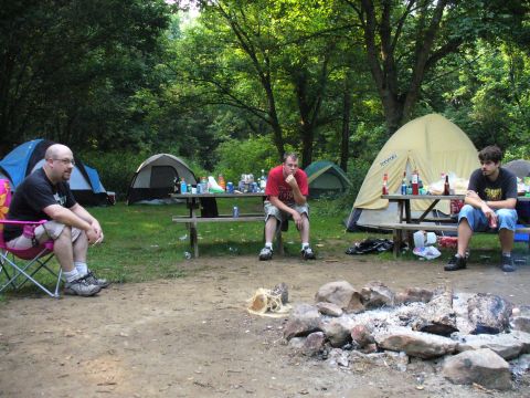 1991 Ford Probe - A group of men relax at a campsite with tents and a fire pit visible.