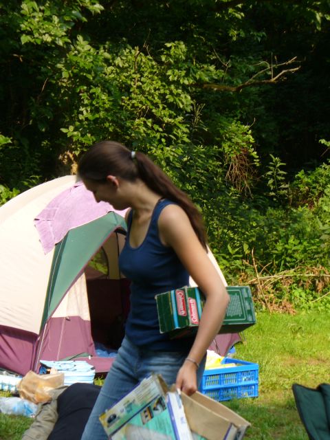 1991 Ford Probe - A woman carries boxes near a tent in a grassy, wooded area.