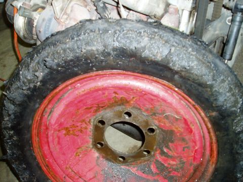 2000 Ford E350 - A severely damaged tire and rim assembly is shown, with engine parts in the background.
