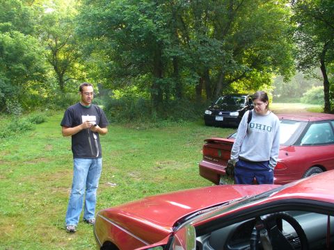 1991 Ford Probe - A red 1991 Ford Probe is parked outdoors next to other vehicles and people.