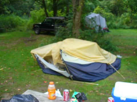 1991 Ford Probe - A black SUV is parked in a grassy area with tents set up nearby.
