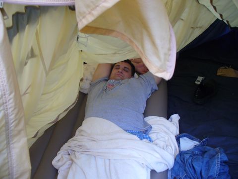 1991 Ford Probe - A man sleeps soundly in a tent, covered by blankets, with personal items nearby.