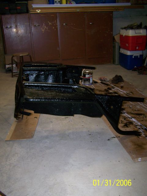 1988 Suzuki Samurai - A vehicle frame section is painted black and placed on cardboard in a garage.
