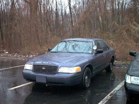 2000 Ford Crown Victoria - A gray 2000 Ford Crown Victoria is parked in a lot with another vehicle visible.