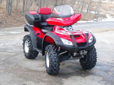 2004 Honda RINCON - This red ATV is parked on a dirt road with trees in the background.