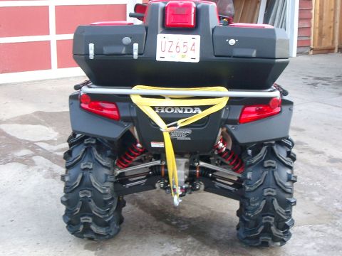 2004 Honda RINCON - Rear view of an ATV with a black storage box and a yellow strap attached.