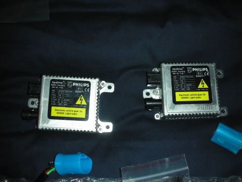 1998 Ford Crown Victoria - Pair of silver Philips XenDrive HID ballast control units laid on dark cloth with blue bulb connectors.