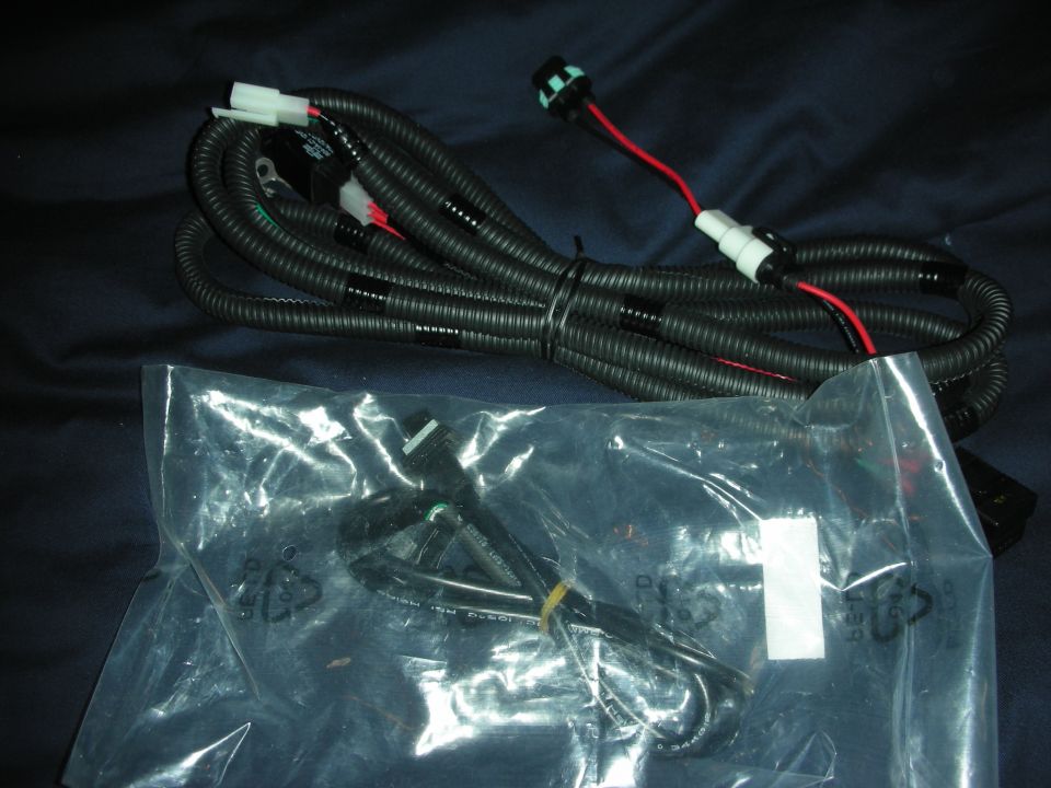 Coiled black wiring harness with red wire and connectors plus a bagged harness