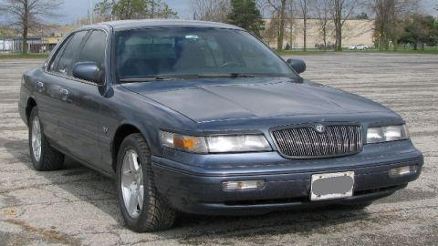 1985 Mercury Grand Marquis - This dark blue sedan, likely a 1995 Mercury Grand Marquis, is shown from the front quarter angle.