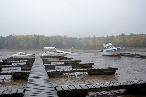 1985 Carver 326 Aft Cabin - Boats are grounded on a dry dock during low tide, with a wooden walkway extending into the scene.