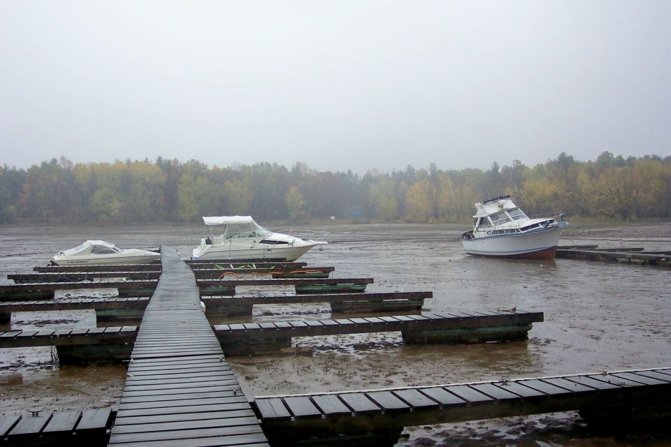 White cabin cruisers stranded on mud flats beside wooden docks on a foggy day