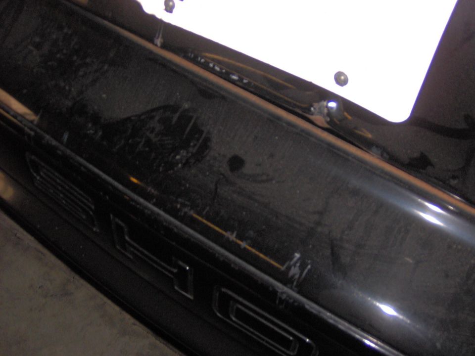Close-up of a black painted tailgate showing raised lettering and mounting hardware