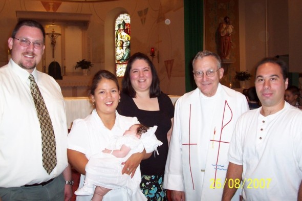 Family and priest posing for a photo at a baptism