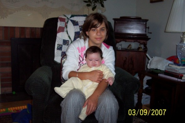 Woman holding a baby indoors, timestamped 03/09/2007