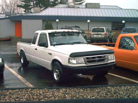 2000 Ford Crown Victoria - A white Ford Ranger pickup truck is parked in a lot next to other vehicles.