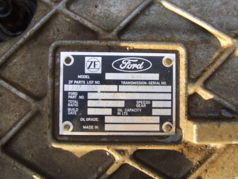 1990 Ford Bronco - A metal plate on a transmission shows Ford and ZF logos, along with part numbers and specifications.