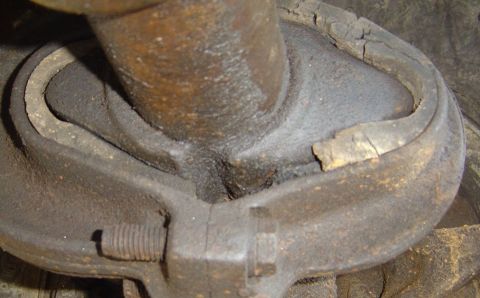 1986 Ford Bronco - Cracked rubber bushing on a vehicle suspension part, indicating wear.