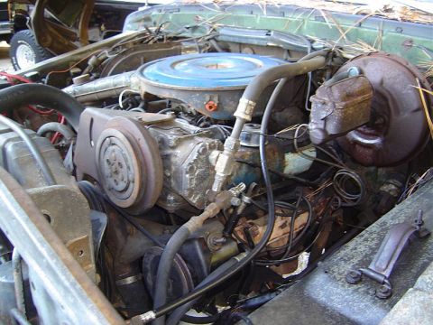 1986 Ford Bronco - The engine bay of a vehicle shows various components, including the air cleaner and compressor, with signs of wear and tear.