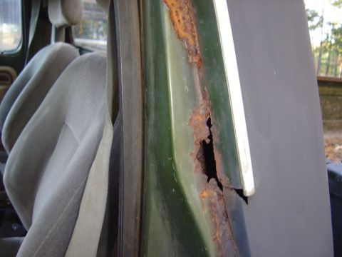 1986 Ford Bronco - Close-up of severe rust on a vehicle's door frame, with interior seats visible.